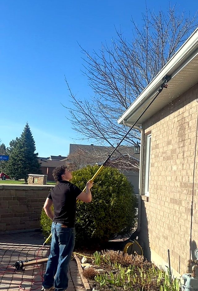 Bungalow windows being cleaned under a clear blue sky