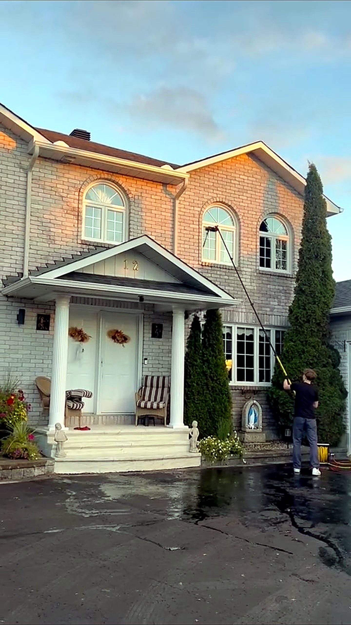Window Brothers cleaning the upper windows of a two-storey Ottawa home with a pure-water pole at golden hour